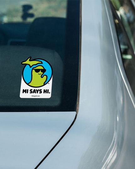 Waving Michigan sticker from the MI Says Hi™ brand on the back window of a car.