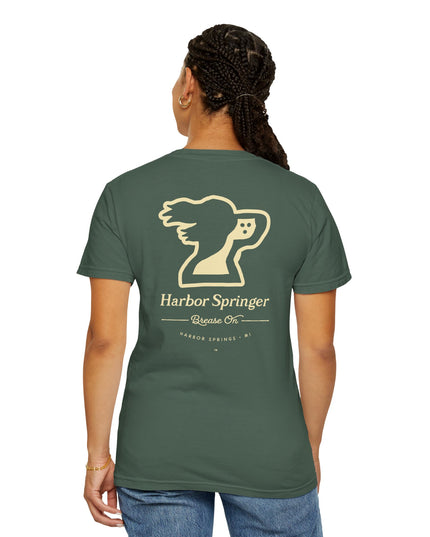 Standing woman with forest green t-shirt by the Harbor Springer brand with a springer spaniel dog logo and Brease On tagline on the back.