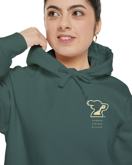 Woman wearing a green color hoodie by the Harbor Springer brand with a springer spaniel dog logo and Harbor Springs Michigan text.