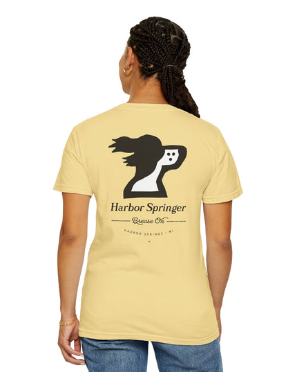 Woman wearing light yellow tee by the Harbor Springer brand with a springer spaniel dog logo and Brease On tagline on the back.