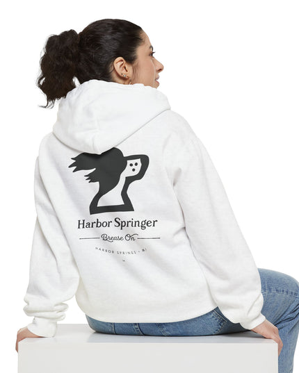 Woman sitting and wearing a white color hoodie by the Harbor Springer brand with a springer spaniel dog logo and Brease On tagline on the back.
